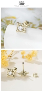 Macro shot of gold vintage iris cross earrings with screw back design and zircon