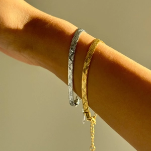 Close-up of 18k gold plated stainless steel flat chain bracelets on wrist in sunlight