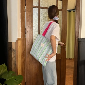 Dettaglio della borsa tote a righe con manici rosa mostrata in un contesto di vita