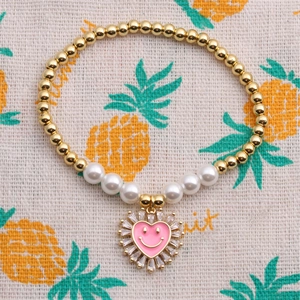Dettaglio del bracciale con perle bianche e ciondolo a cuore in zircone rosa