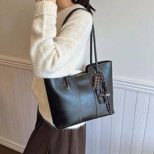 Minimalist black tote bag with white stitching and decorative charms for women