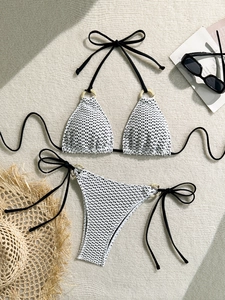 Detailed view of crochet knit bikini texture with marble ring accents on beach mat