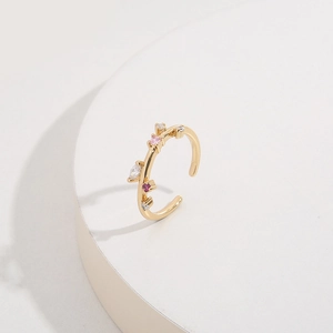 Golden adjustable open ring with sparkling pink and red marquise-cut gems on a stand