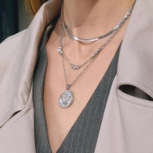 Three-layer silver necklace with flat snake chain and angel relief pendant on model
