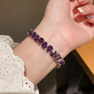 Detailed macro shot of a purple teardrop-cut zircon bracelet on a lace sleeve