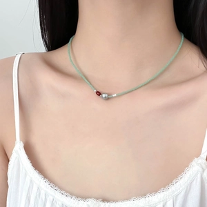 Collier frais en perles vert menthe avec agate rouge et perle baroque sur la clavicule