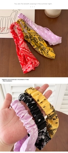 Detail showing various colors of paisley print fabric headbands with elastic twist design
