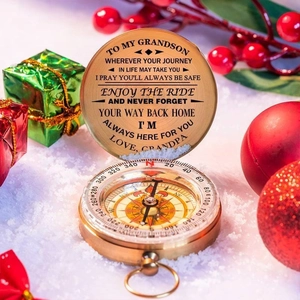 Golden engraved compass gift with custom message in a snowy festive holiday background