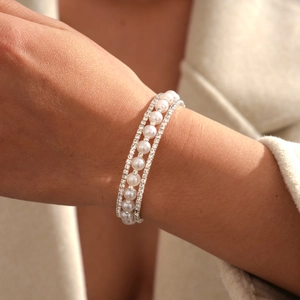 Detailed view of triple-layer bracelet with sparkling rhinestones and white pearls