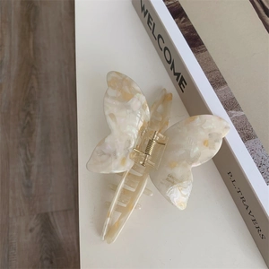 Detail showing marble texture acetate butterfly hair claw clip with golden metal spring