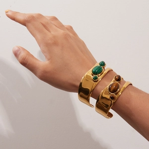 Detailed view of wide gold-plated open bangles featuring malachite and tiger eye stones