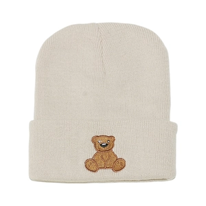Detail of cute brown bear embroidery on a beige knitted beanie cap for winter