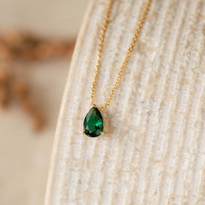 Macro shot of 18k gold plated necklace featuring a pear-cut green zircon pendant