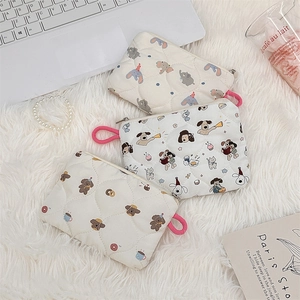 Flat lay of small quilted cosmetic bags featuring cartoon elephants and bears on plush decor