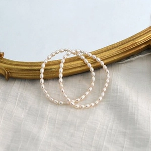 Detail of 14K gold plated baroque pearl bracelet set on elegant white linen fabric