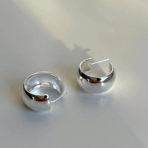 Macro shot of silver C-shaped chunky stud earrings with high-polish mirror finish