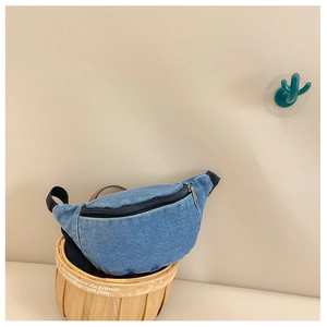 Close-up of blue denim kids waist bag with black zipper in a woven basket