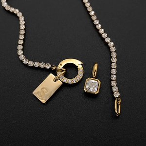 Macro detail of 14K gold plated titanium necklace with letter S tag and crystals.