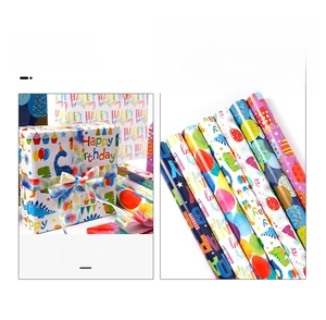 Detail of colorful birthday wrapping paper with balloon and dinosaur prints and ribbons
