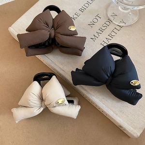 Detail of padded bow hair claws in dark brown, black, and beige with golden accents