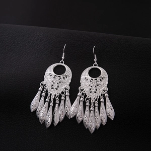 Detailed view of silver ethnic leaf earrings with hollow tassel on black leather