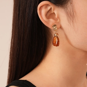 Close-up of vintage geometric amber acrylic earrings with hammered gold metal accents