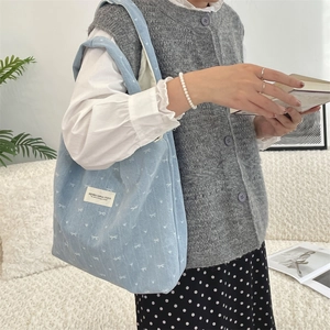 Détail du sac cabas en velours côtelé bleu clair avec motif nœud et étiquette en toile