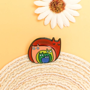 Detailed close-up of a stacked rainbow cat enamel pin on a natural woven mat background