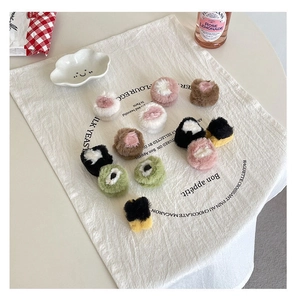Flat lay of colorful plush fur hair rings on a white linen mat with decorative props