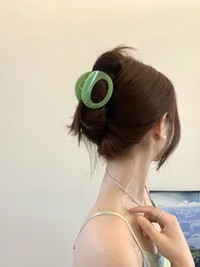 Macro detail of grass green oval claw clip holding a classic hair updo in style