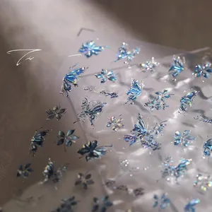 Macro shot of 3D iridescent blue butterfly and floral nail art stickers with silver embossing