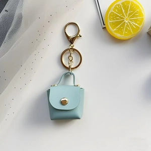 Detail of light blue faux leather mini bag keychain with golden buckle and snap button
