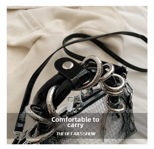 Close-up of silver spiral metal handles on a white snakeskin textured handbag