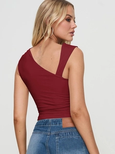 Gros plan sur le débardeur asymétrique rouge foncé coupe ajustée avec un jean bleu