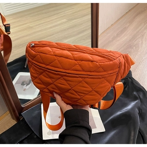 Close-up of orange quilted nylon crossbody chest bag with adjustable strap and buckle
