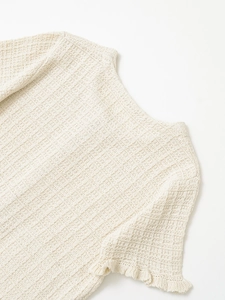 Close-up of cream knit cardigan featuring waffle texture and ruffled cuff detail