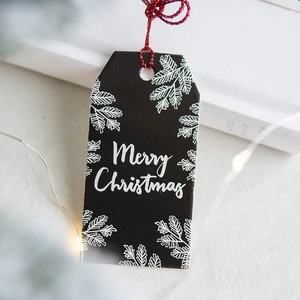 Black Christmas gift tags with white cedar tree patterns and red string for festive decor