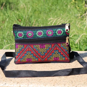 Detailed close-up of ethnic crossbody bag with colorful embroidery and double zippers