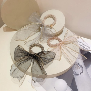 Detail of four mesh bow hair ties in grey, pink, black and champagne with bead accents