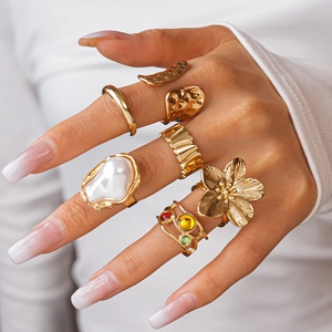 Detail of gold floral rings set with irregular pearls and colorful gemstones on hand