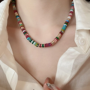 Close-up of colorful beaded choker with 18k gold plated accents on white shirt