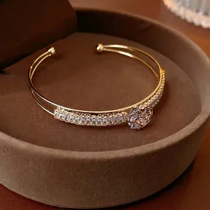 Gold open cuff bracelet with zircon flowers in a luxury velvet jewelry box