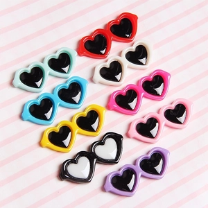 Eight colorful heart-shaped resin pet glasses clips neatly arranged on a striped background