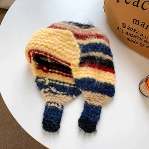 Detail of multi-color striped knitted earflap hat with thick wool texture and tassels