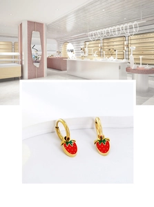 Detailed view of red strawberry pendant earrings with gold finish and enamel texture