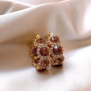 Detail of 18k gold plated hoop earrings with brown crystals on champagne silk fabric