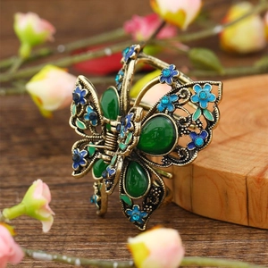 Vintage bronze butterfly hair claw clip with colorful rhinestones on a rustic wood surface