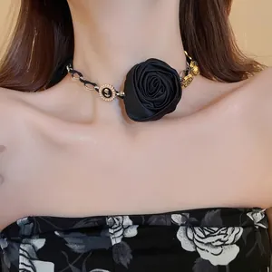 Elegante collana choker con rosa di stoffa nera, perle e accenti metallici dorati