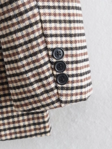 Detail von drei schwarzen Knöpfen am Ärmel eines gebürsteten Blazers mit Hahnentrittmuster