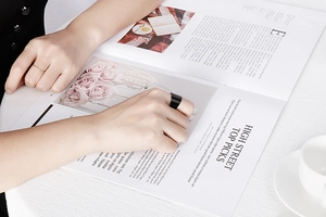 Minimalist wide black and slim silver titanium rings on hand with lifestyle magazine